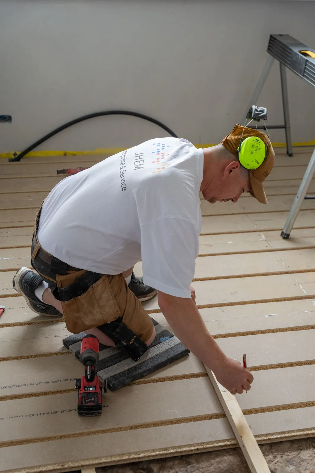 Håndværker fra JHEM monterer gulvplader på strøer under en renovering