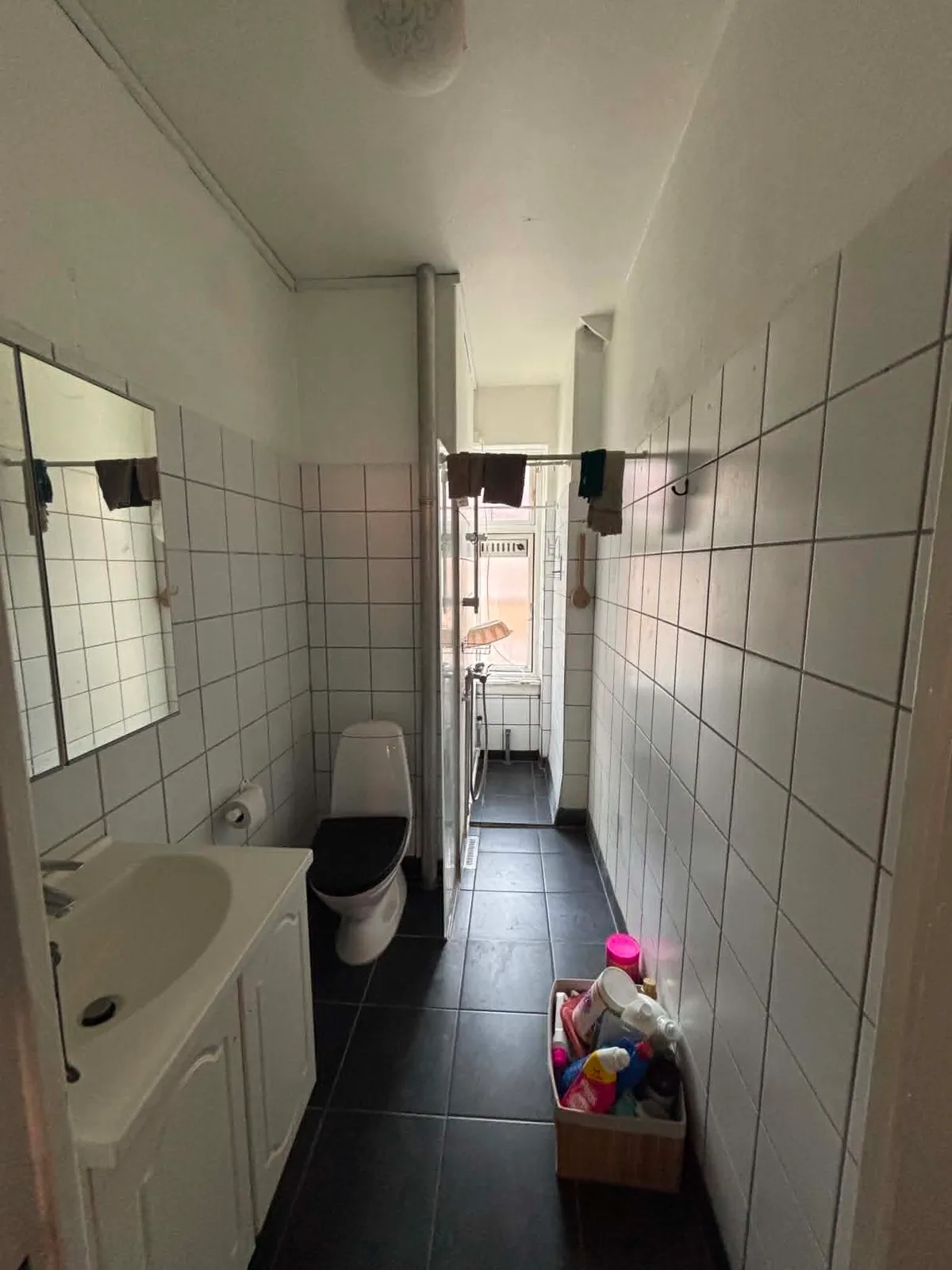 Det gamle badeværelse med hvide fliser og badekar før renoveringen