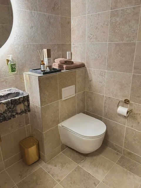 Væghængt toilet mod travertin og terrazzo